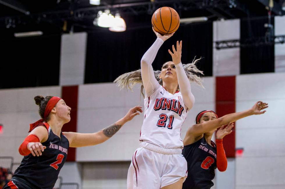 UNLV Rebels forward/center Katie Powell (21) goes up for a shot while defenders New Mexico Lobos guard Tesha Buck (2) and New Mexico Lobos guard Cherise Beynon (0) fall on her sides at Cox Pavilio ...