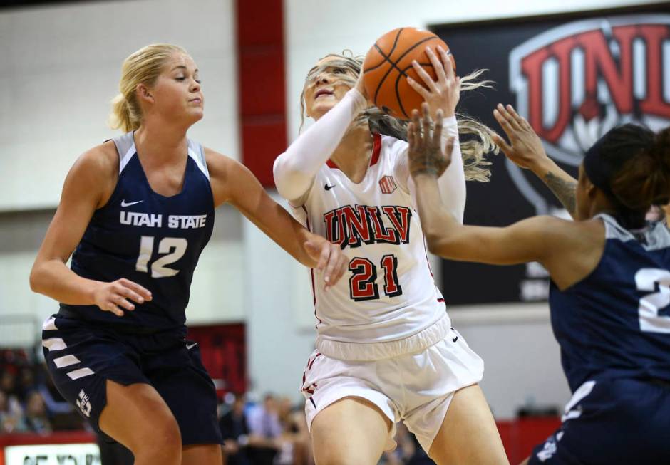 UNLV Lady Rebels forward/center Katie Powell (21) drives as Utah State Aggies guard/forward Hailey Bassett (12) defends during the second half of a basketball game at the Cox Pavilion in Las Vegas ...