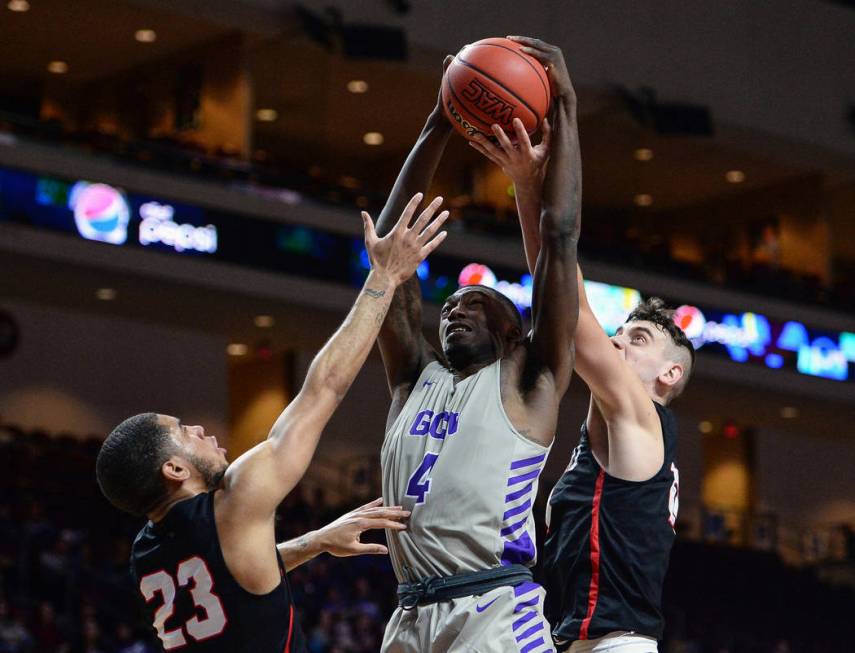 Grand Canyon forward Oscar Frayer (4) jumps up for a rebound while being guarded by Seattle guard Terrell Brown (23) and guard Rip Economou (11) in the first half of the opening round of the Weste ...