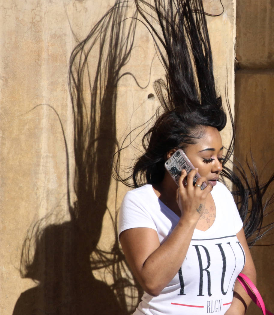 A woman has her hair blown by heavy wind as she talks on her phone on Third street on Wednesday, March. 13, 2019, in Las Vegas. Bizuayehu Tesfaye Las Vegas Review-Journal @bizutesfaye