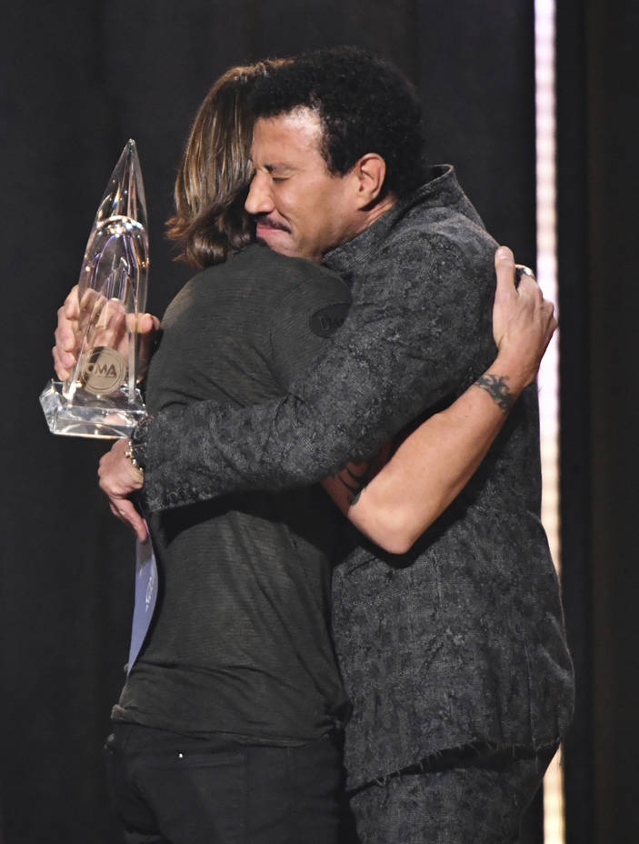 Lionel Richie, right, embraces Keith Urban, winner of the award for entertainer of the year at the 52nd annual CMA Awards at Bridgestone Arena on Wednesday, Nov. 14, 2018, in Nashville, Tenn. (Cha ...