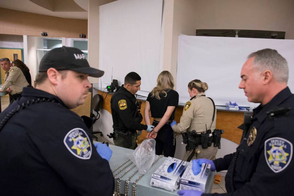 Marshal Johnny Patino, second from left, and Metro Officer B. Muenzenmeyer, second from right, process a suspected impaired driver at the Metro Traffic Bureau as part of a "DUI blitz" on ...