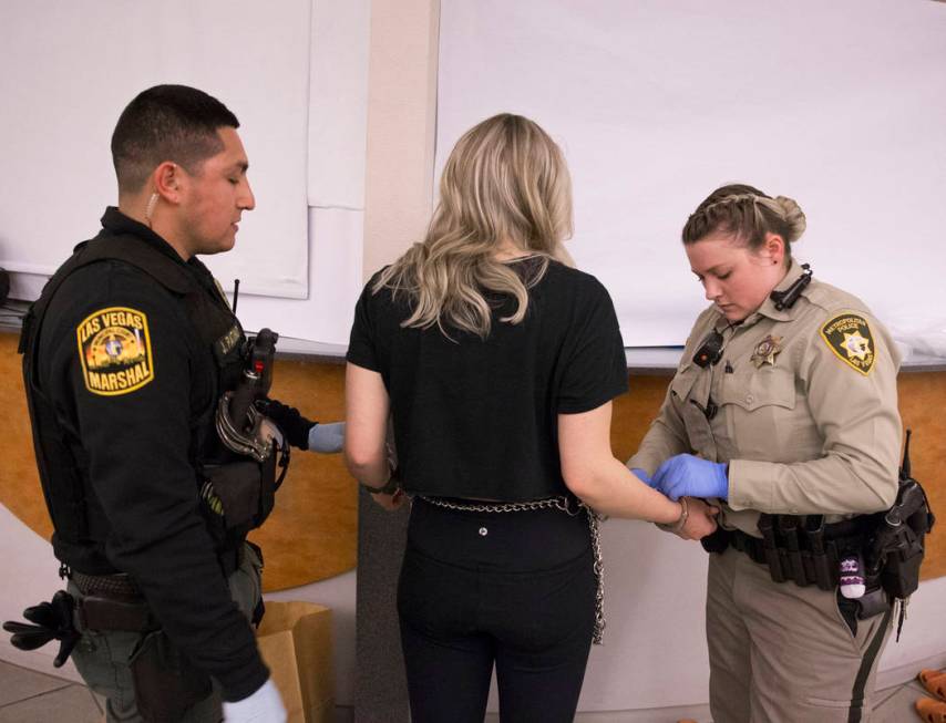 Marshal Johnny Patino, left, and Metro Officer B. Muenzenmeyer, right, process a suspected impaired driver at the Metro Traffic Bureau as part of a "DUI blitz" on Thursday, March 14, 201 ...