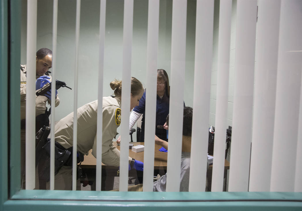 A suspected impaired driver, right/bottom, has blood taken by EMT Katharine York, middle, with assistance from Metro officers at the Metro Traffic Bureau as part of a "DUI blitz" on Thur ...