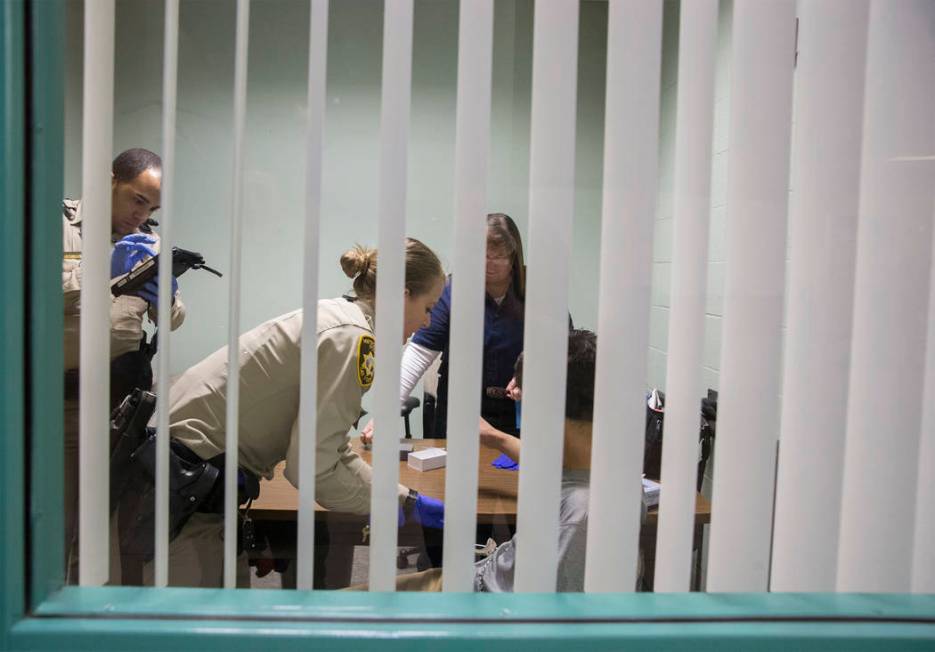 A suspected impaired driver, right/bottom, has blood taken by EMT Katharine York, middle, with assistance from Metro officers at the Metro Traffic Bureau as part of a "DUI blitz" on Thur ...