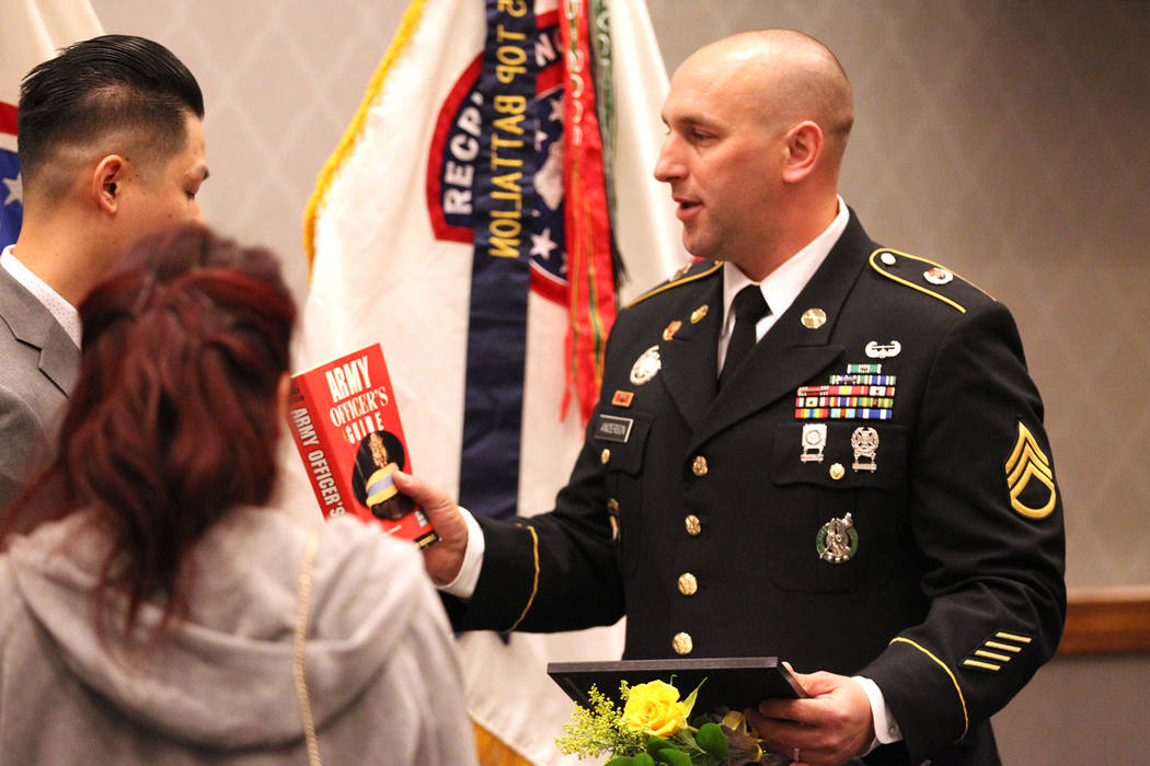 Anthony Hua receives a book as a gift from U.S. Army Staff Sgt. Zachary Anderson, a health care recruiter, after getting sworn in as U.S. Army Reserve captain during a ceremony at the Hampton Inn ...