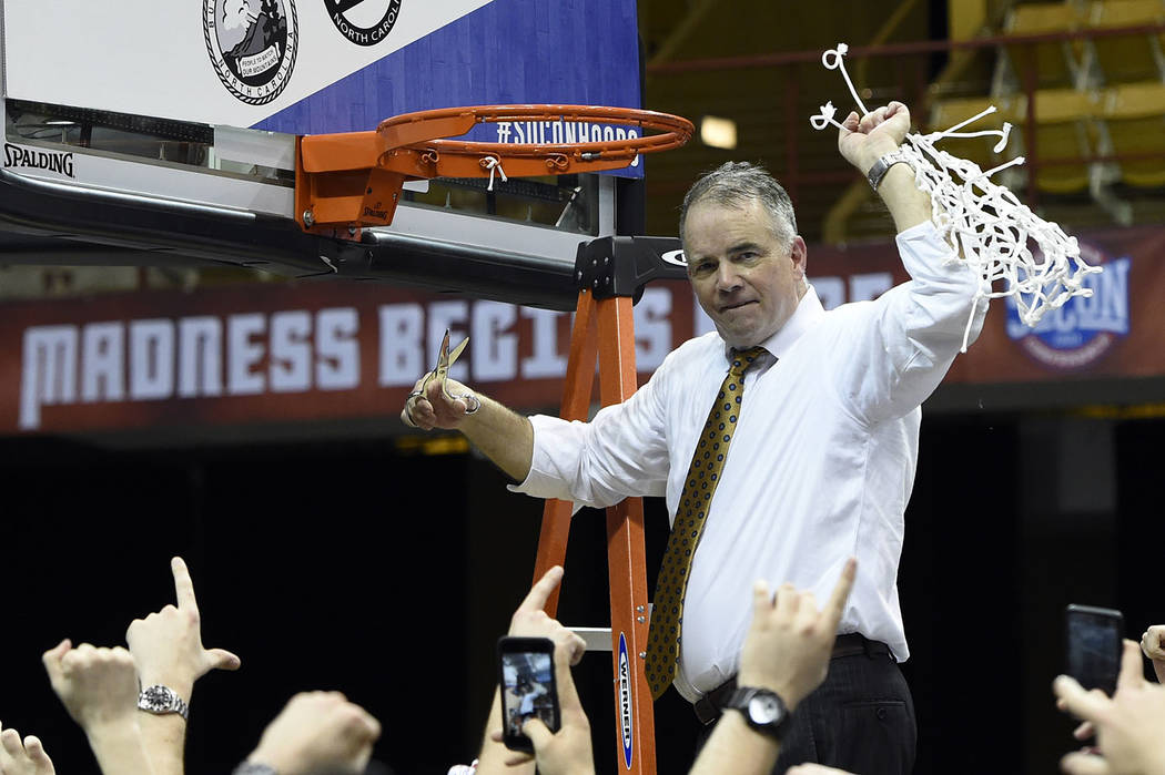 Wofford head coach Mike Young raises the basketball net in the air to celebrate his team's 70-58 win over UNC-Greensboro for the Southern Conference tournament championship, Monday, March 11, 2019 ...