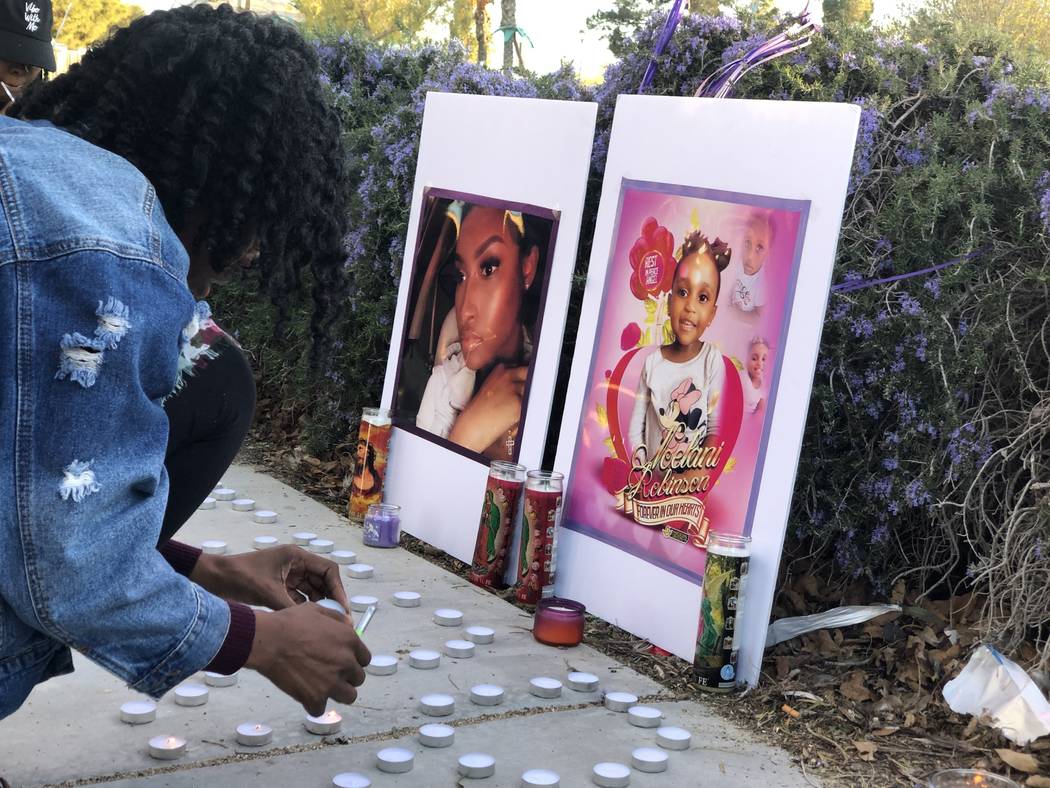 A woman lights a candle during a vigil on Saturday, March 16, 2019, in North Las Vegas for Sierra Robinson, 24, and her daughter, 2-year-old Noelani Robinson. Police said Sierra Robinson, of Las V ...