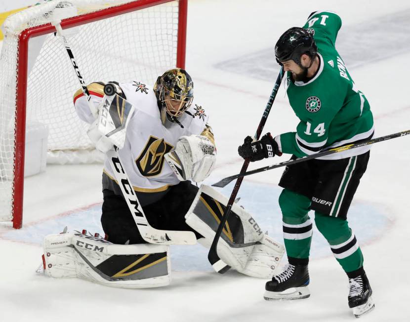 Vegas Golden Knights goaltender Marc-Andre Fleury (29) deflects a shot with his glove under pressure from Dallas Stars left wing Jamie Benn (14) in the third period of an NHL hockey game in Dallas ...