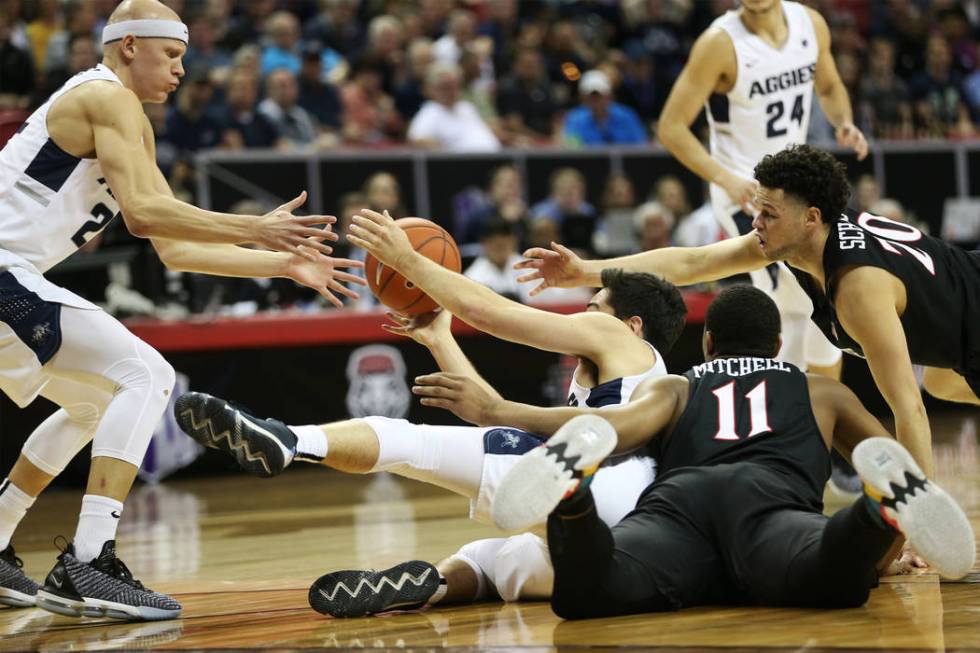 Utah State Aggies guard Abel Porter (15) makes a pass to guard Brock Miller (22) under pressure from San Diego State Aztecs forward Matt Mitchell (11) and guard Jordan Schakel (20) in the first ha ...