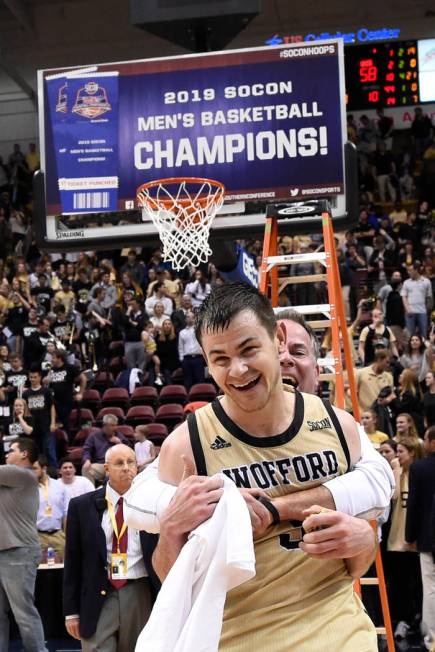 Wofford guard Fletcher Magee (3) receives a hug after his team defeated UNC-Greensboro 70-58 for the Southern Conference tournament championship, Monday, March 11, 2019, in Asheville, N.C. Magree ...