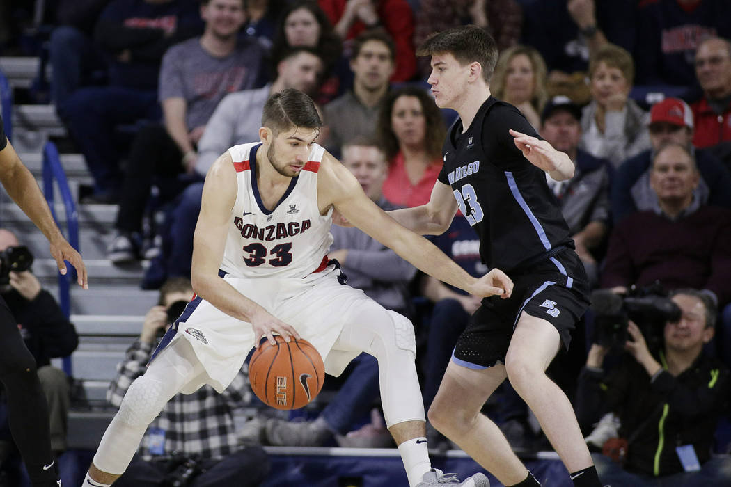 Gonzaga forward Killian Tillie (33) dribbles the ball while defended by San Diego guard Finn Sullivan (23) during the first half of an NCAA college basketball game in Spokane, Wash., Saturday, Feb ...