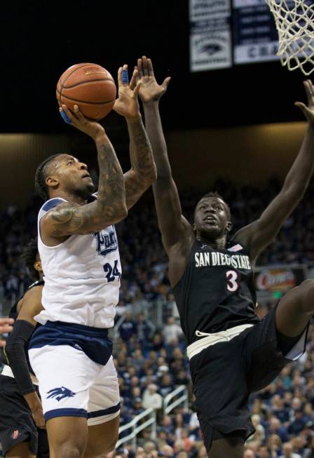 Nevada forward Jordan Caroline (24) drives past San Diego State guard Jeremy Hemsley (42) and guard Jordan Schakel (20) in the second half of an NCAA college basketball game in Reno, Nev., Saturda ...