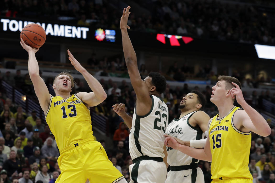 Michigan's Ignas Brazdeikis (13) goes up for a shot against Michigan State's Xavier Tillman (23) during the first half of an NCAA college basketball championship game in the Big Ten Conference tou ...