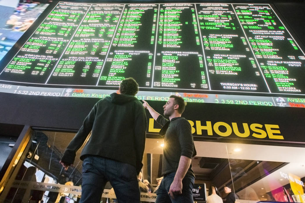 Evan Thoma, right, and Matt Castagna, both from Chicago, Ill., discuss odds during the first day of the NCAA Tournament at the Westgate Sportsbook on Thursday, March 21, 2019, at Westgate, in Las ...