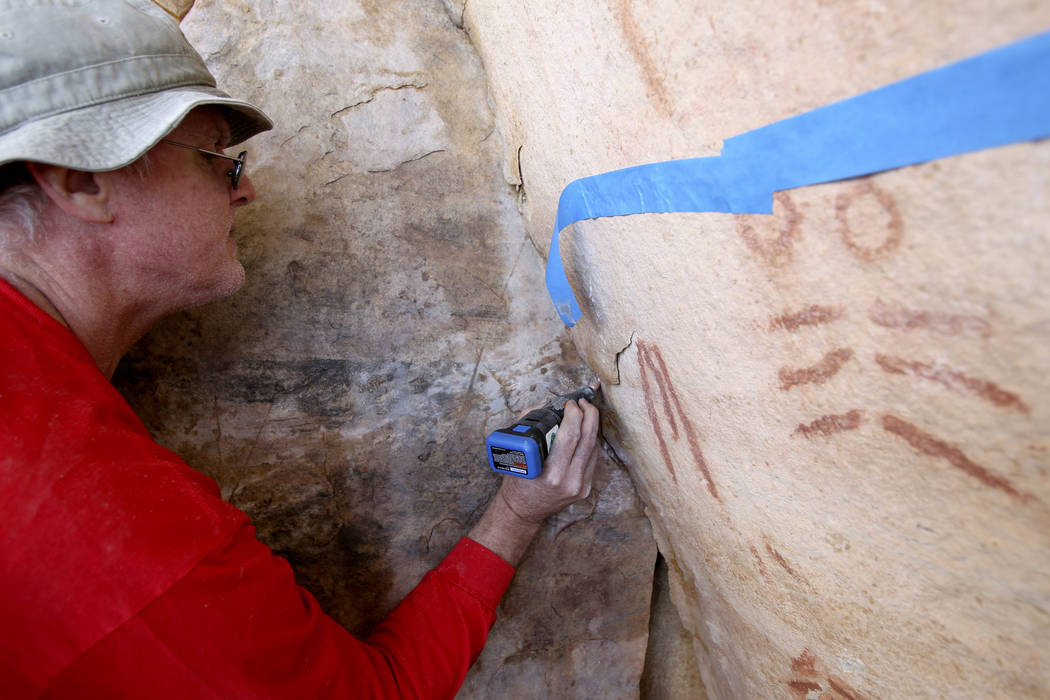 Wyatt Mulvey, a volunteer with Friends of Red Rock Canyon, works Thursday, May 19, 2011, to restore an ancient rock art site near Lost Creek that was damaged by graffiti vandals in November. (K.M ...