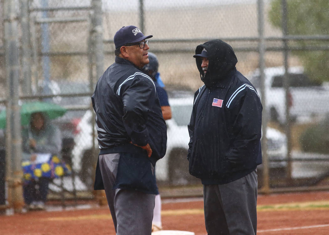 Umpires talk as rain comes down in the first inning of a softball game at Shadow Ridge High School in Las Vegas on Wednesday, March 20, 2019. (Chase Stevens/Las Vegas Review-Journal) @csstevensphoto