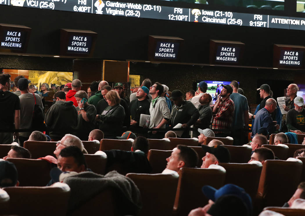 Fans lined up to place their bets as others watch a basketball game during the first day of the NCAA basketball tournament at the Westgate sports book in Las Vegas on Thursday, March 16, 2019. (Bi ...