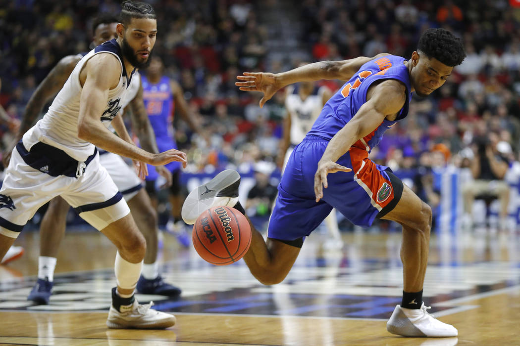 Nevada forward Caleb Martin, left, steals the ball from Florida guard Jalen Hudson during a first round men's college basketball game in the NCAA Tournament, Thursday, March 21, 2019, in Des Moine ...