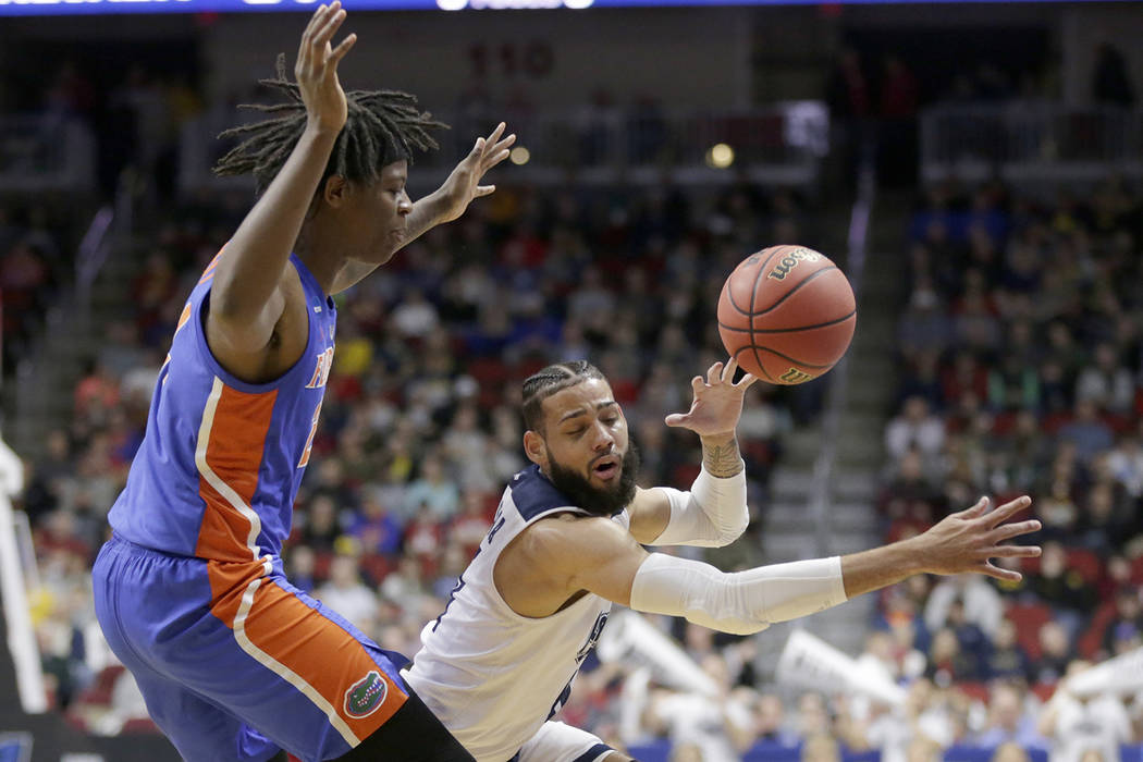 Nevada's Cody Martin, right, loses control of the ball as he drives around Florida's Andrew Fava, left, during the first half of a first round men's college basketball game in the NCAA Tournament ...