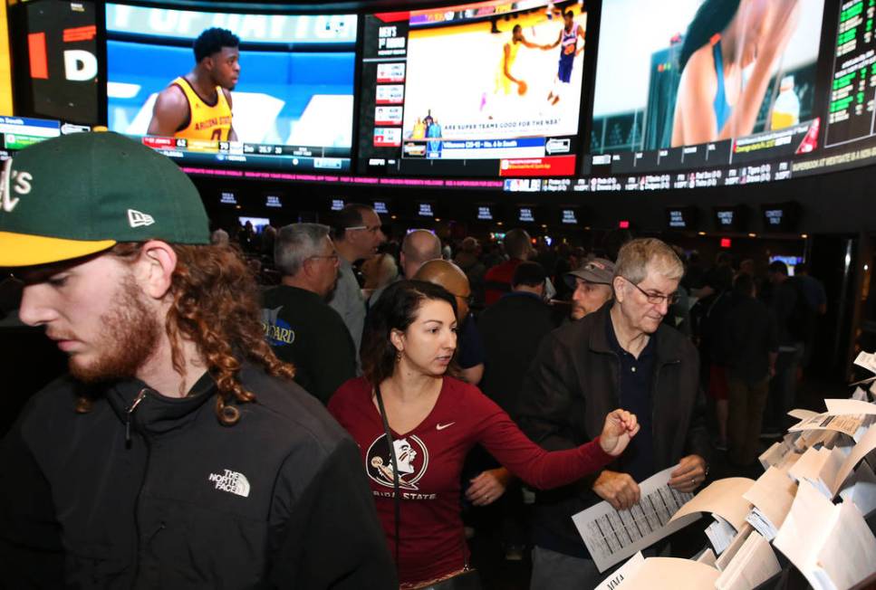 Fans, including Ivette Abramyan, center, of Jacksonville, Fla,., lined up to place their bets during the first day of the NCAA basketball tournament at the Westgate sports book in Las Vegas on Thu ...