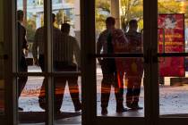 Plainclothes police officers walk out of the Las Vegas Convention Center after executing a sear ...