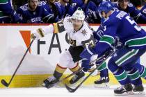 Vegas Golden Knights' Max Pacioretty (67) fights for the puck against Vancouver Canucks' Derrick Pouliot (5) during the second period of an NHL hockey game in Vancouver, British Columbia, Saturday ...