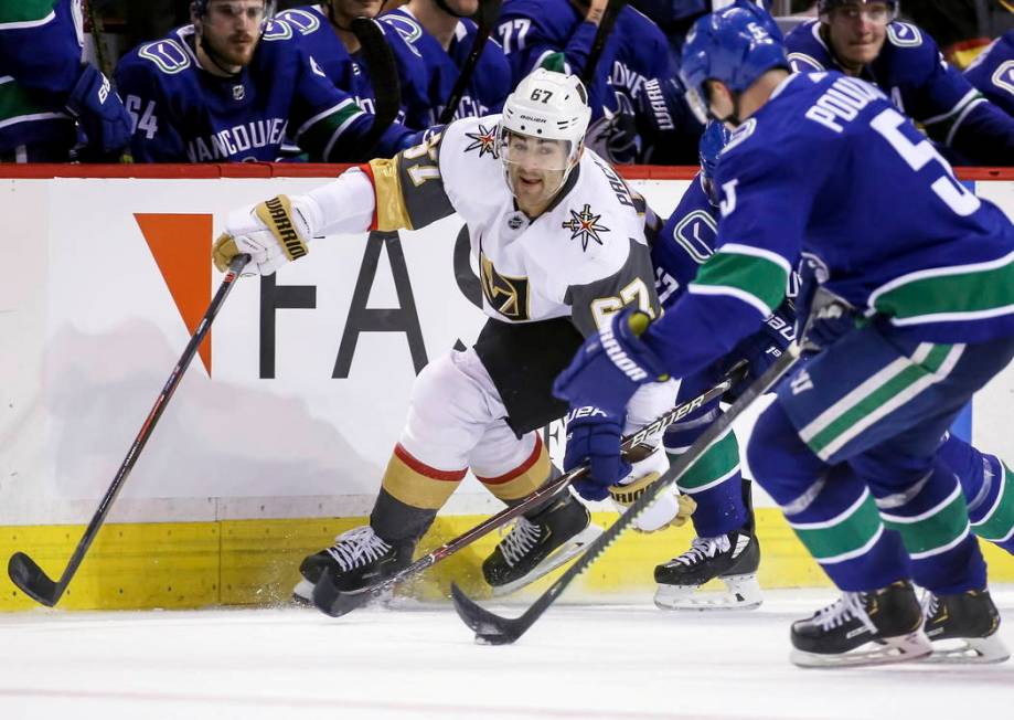 Vegas Golden Knights' Max Pacioretty (67) fights for the puck against Vancouver Canucks' Derrick Pouliot (5) during the second period of an NHL hockey game in Vancouver, British Columbia, Saturday ...