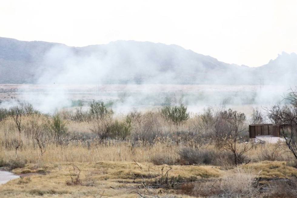 Smoke arises after a brush fire is put out at the Wetlands Park, north of Sam Boyd Stadium, in ...