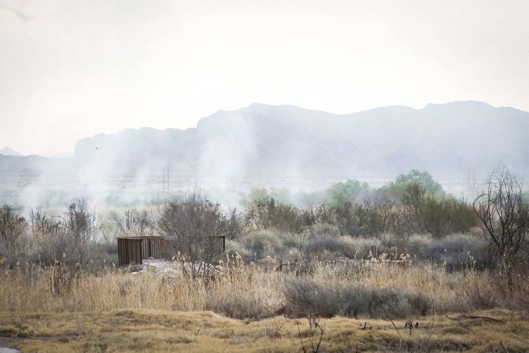 Smoke arises after a brush fire is put out at the Wetlands Park, north of Sam Boyd Stadium, in ...