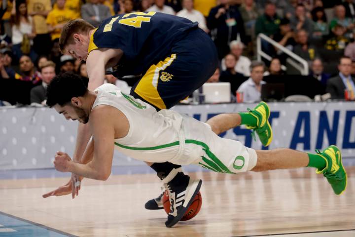 UC Irvine forward Tommy Rutherford, top, and Oregon guard Ehab Amin vie for a loose ball during ...