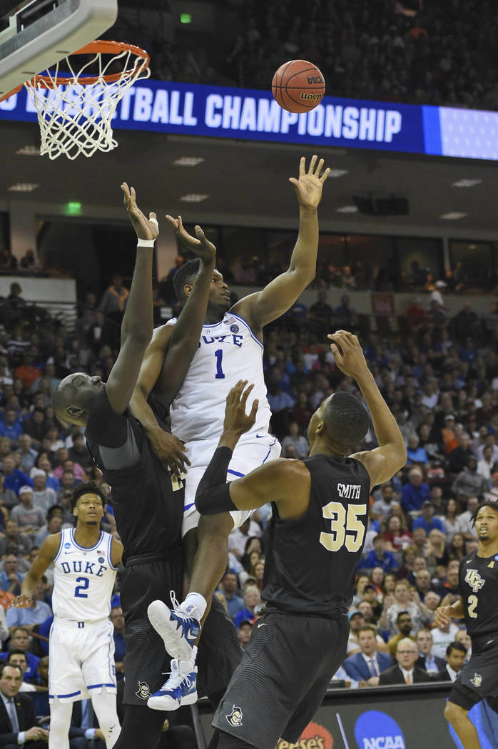 Duke's Zion Williamson (1) is pressured by Central Florida's Tacko Fall, left, and Collin Smith during the second half of a second round men's college basketball game in the NCAA Tournament in Col ...