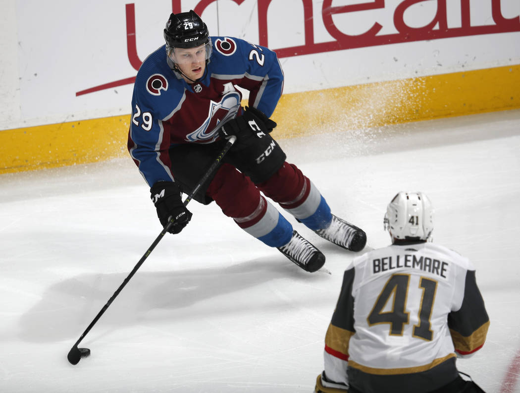 Colorado Avalanche center Nathan MacKinnon, top, looks to pass the puck as Vegas Golden Knights ...