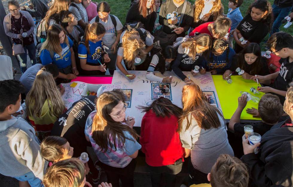 A large group of kids sign a poster honoring the memory of Jonathan Smith, 12, during a vigil f ...