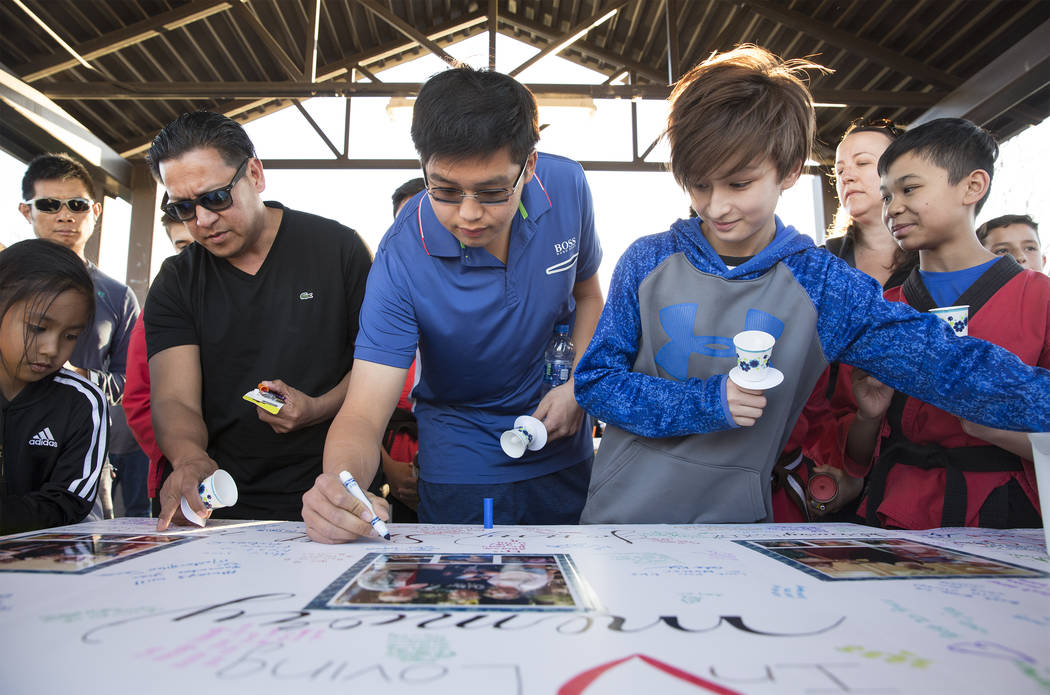 Attendees sign a poster honoring the memory of Jonathan Smith, 12, during a vigil for Smith at ...