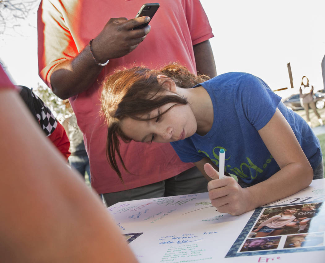 Sayuri Reyes, 8, signs a poster honoring the memory of Jonathan Smith, 12, during a vigil for S ...