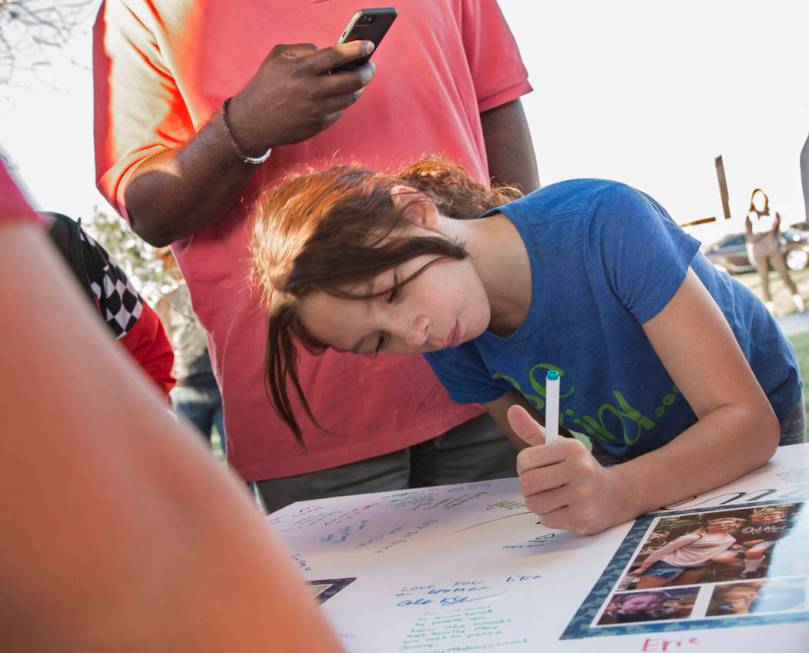 Sayuri Reyes, 8, signs a poster honoring the memory of Jonathan Smith, 12, during a vigil for S ...