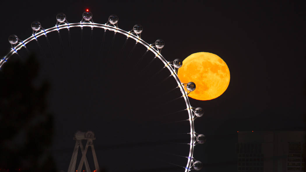 A full moon rises behind the High Roller observation wheel on the Strip in Las Vegas on Sunday, ...