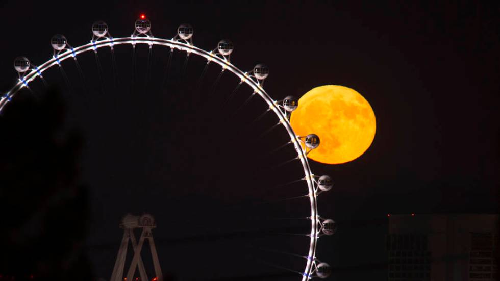 A full moon rises behind the High Roller observation wheel on the Strip in Las Vegas on Sunday, ...