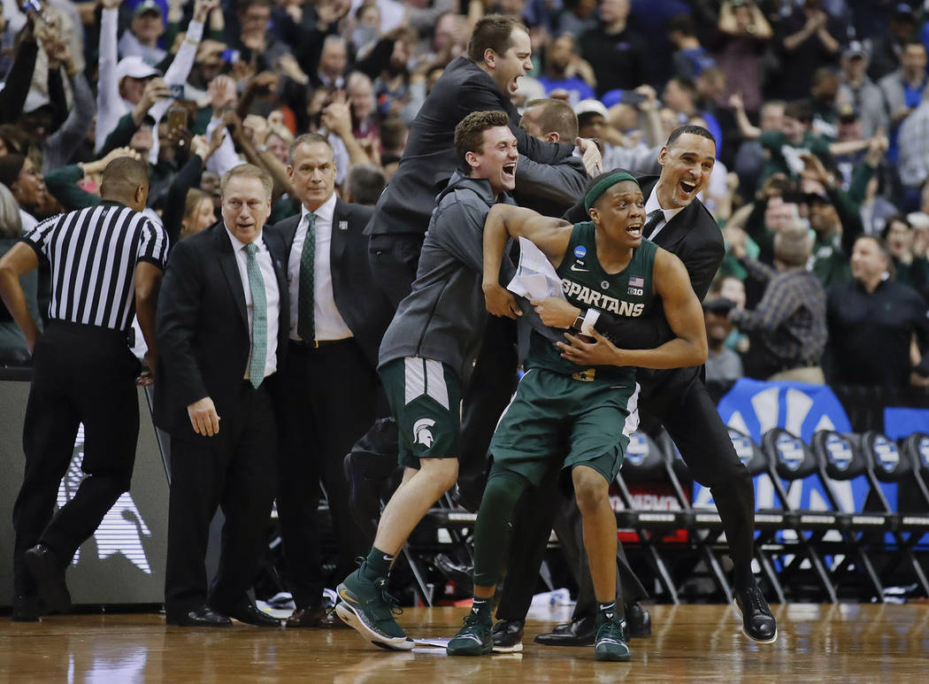 Michigan State guard Cassius Winston (5) begins to celebrate with members of his team after def ...