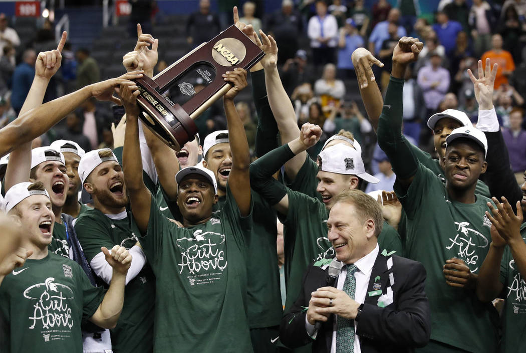 Michigan State guard Cassius Winston holds up the NCAA men's East Regional trophy as he celebra ...