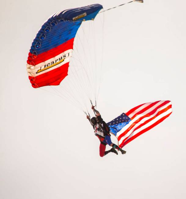 A parachuter arrives with the American flag during the NHRA Mello Yellow Drag Racing Series on ...