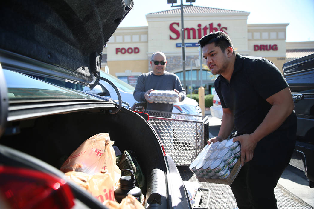 Michael Pabua, right, with his father Jun, load their car with groceries after shopping at Smit ...