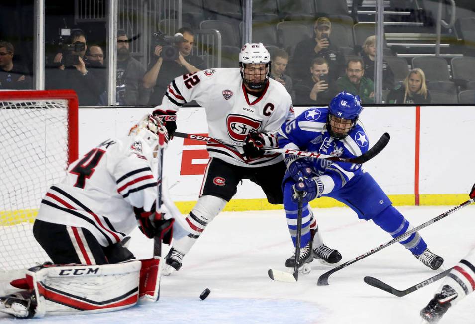 Air Force's Evan Giesler (15) battles to get the puck past St. Cloud State goalie David Hrenak ...