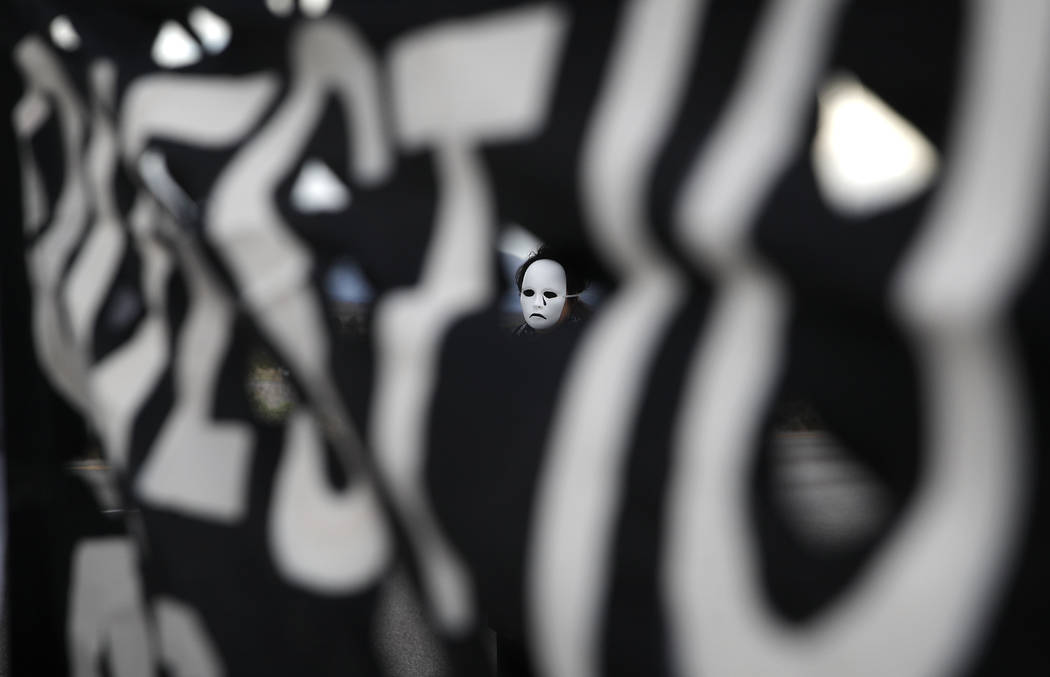 A person wears a mask during a protest against drone warfare at the entrance of Creech Air Forc ...