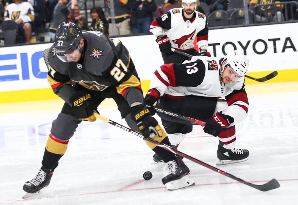 Golden Knights defenseman Shea Theodore (27) tries to get the puck from Arizona Coyotes center ...