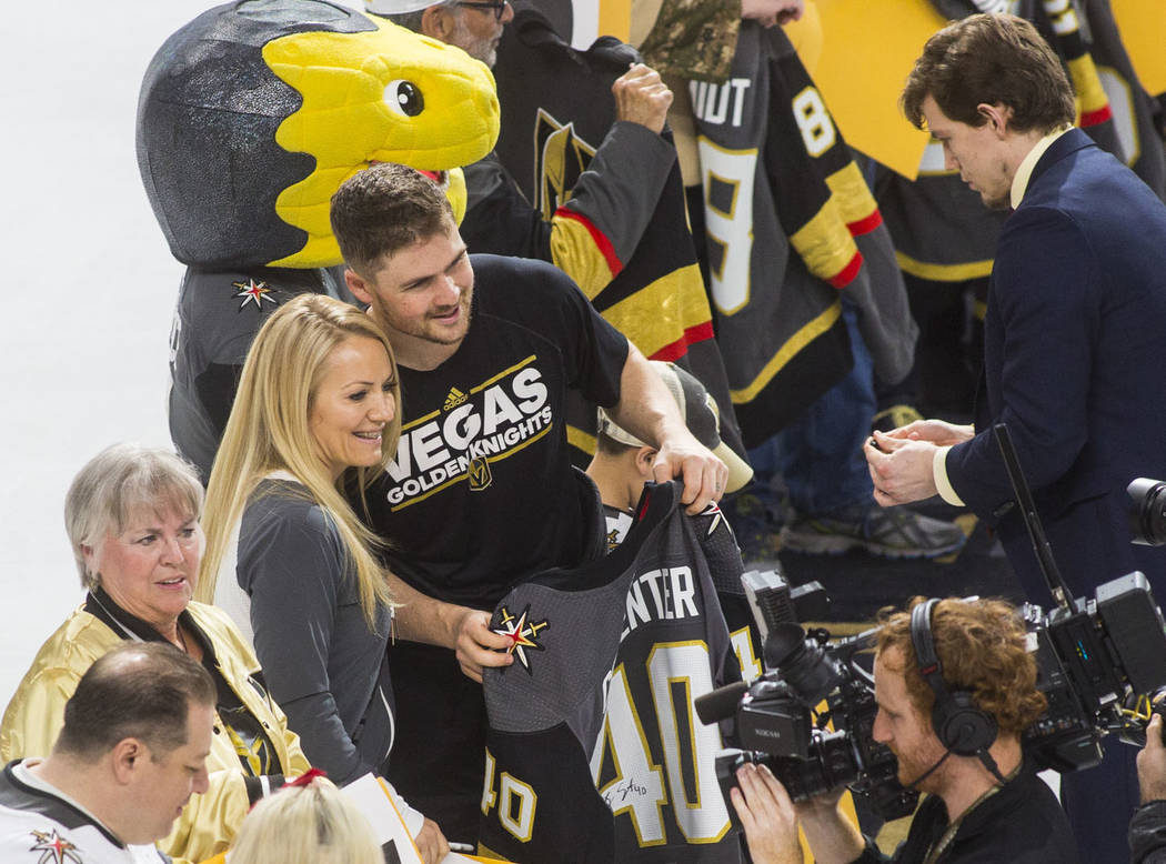Golden Knights center Ryan Carpenter (40) poses with a lucky fan while joining players in signi ...
