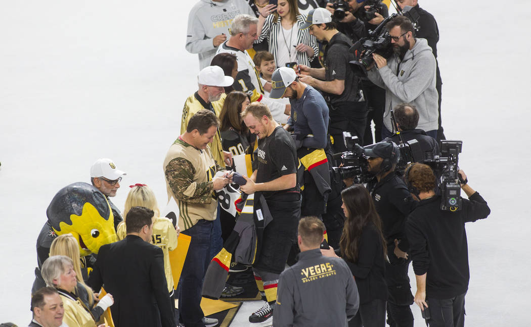 Golden Knights defenseman Nate Schmidt, center left, joins other players in signing and giving ...
