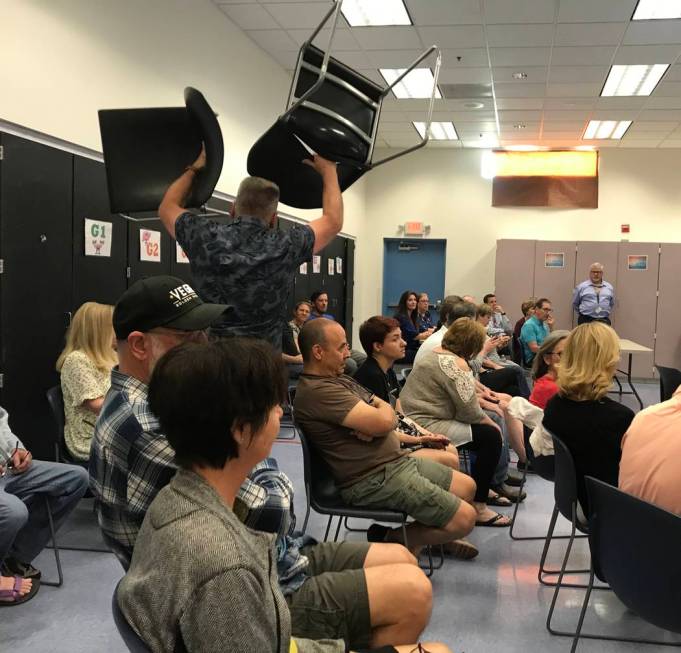 Residents bring in more chairs to accommodate the turnout of residents to a community meeting o ...