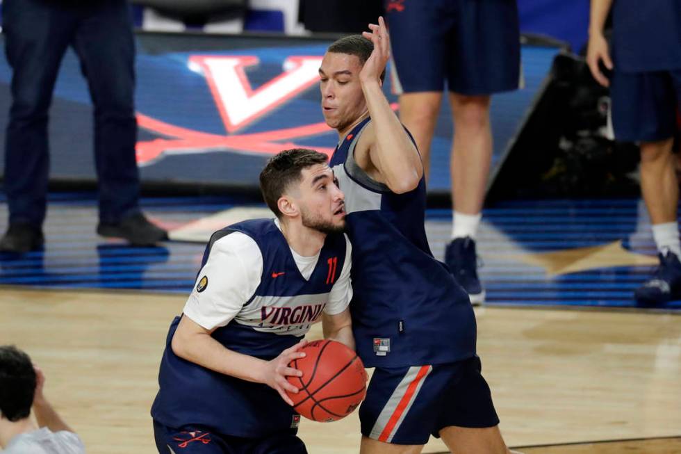 Virginia's Ty Jerome (11) drives against Francesco Badocchi during a practice session for the s ...